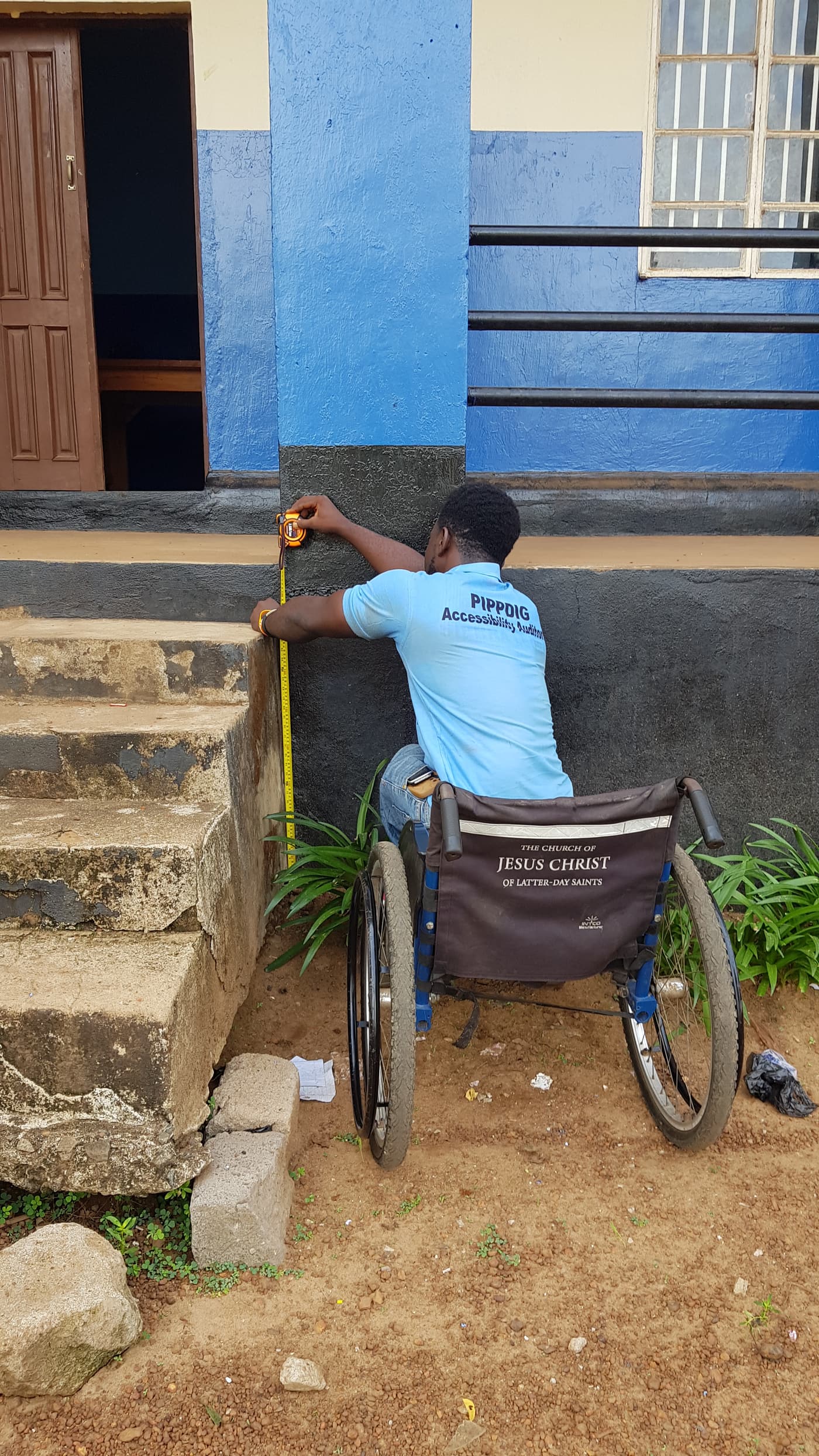 A WESOFOD accessibility auditor in a wheelchair measures the height of a step at a public building